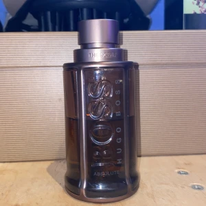 Hugo Boss The Scent Absolute 100ml - Hugo Boss The Scent Absolute Eau de Parfum i en snygg mörkbrun glasflaska med metallisk bronsfärgad kork. Flaskan rymmer 100 ml men som du kan se så är de halva kvar typ så, frågor o pris kan diskuteras, 