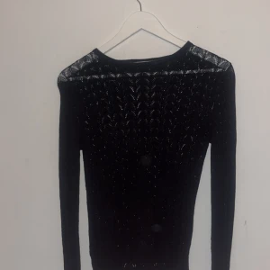 Svart stickad tröja från Zara - Snygg svart stickad tröja från Zara med lång ärm och genombrutet mönster. Tröjan har en smal passform och är perfekt för dig som gillar stilrena och trendiga plagg. Materialet är mjukt och stretchigt, vilket gör den bekväm att bära hela dagen.
