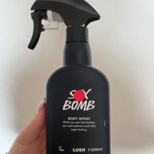 Lush Sex Bomb Body Spray 200ml - S*x Bomb Body Spray från Lush i svart plastflaska med spraymunstycke. Doften har inslag av jasmin och clary sage, perfekt för dig som gillar blommiga och sensuella toner. Flaskan rymmer 200 ml och är vegansk. Har endast används fåtal gånger för att det inte riktigt är min sorts av doft tyvärr….          original pris-400kr