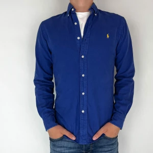 Ralph Lauren Skjorta - Nu har vi nöjet att erbjuda en klassisk  skjorta från det välkända varumärket Ralph Lauren. Plagget är i storlek Small och är i mycket gott skick, utan några synliga defekter. Modellen på bilden är 182 cm lång och väger 75 kg, vilket kan ge en god indikation på tröjans passform.