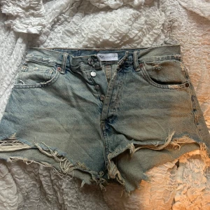 Zara jeansshorts med slitna detaljer - Snygga ljusblå jeansshorts från Zara med råa, fransiga kanter och slitna detaljer. Dom är köpta här på Plick men knappt använda av varken mig eller tidigare ägaren. Storlek 38 men skulle säga att dom är små i storleken💓💓💓💓💓