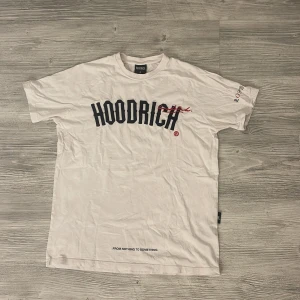 Vit t-shirt från Hoodrich  - T-shirt i stilren design med perfekt passform. Tillverkad i mjuk och slitstark bomull som känns skön mot huden och håller formen tvätt efter tvätt. Den tidlösa modellen passar både vardag och fritid – enkel att matcha, svår att tröttna på. Passar alla som vill ha ett plagg med både komfort och stil i ett. 