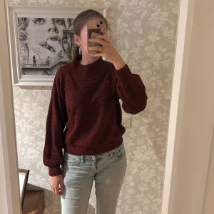 Vinröd stickad tröja från SHEIN - Mysig vinröd stickad tröja från SHEIN med avslappnad passform och ribbade muddar. Tröjan har högre krage och diskreta detaljer i stickningen som ger en cool look. Perfekt till jeans eller kjol för en chill stil.