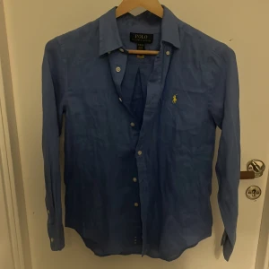Ny Blå linneskjorta från Polo Ralph Lauren - Säljer en helt oanvänd blå skjorta i linne från Polo Ralph Lauren. Skön och luftig känsla tack vare linnematerialet. Endast testat! Säljer pga att den inte kommer till användning storleken är 10-12 år men sitter mycket större ungefär från 160-165 för att polo Ralph lauren är stora i storlek! Passar mig som är 163/164! Kosta runt 1000kr nypris kanske lite mer skriv om ni undrar något mvh Arvid