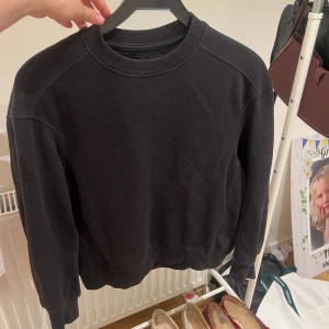 Svart sweatshirt från 157, XS - En basic svart sweatshirt från 157 i storlek XS. Tröjan har rund halsringning, ribbade muddar vid ärmslut och nederkant samt lång ärm. Perfekt för en chill och avslappnad stil.