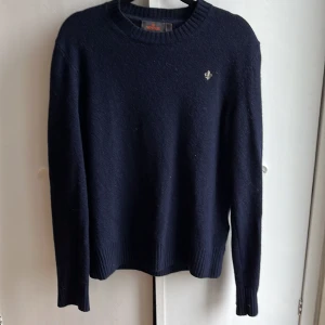 Mörkblå ulltröja från Morris - Klassisk mörkblå stickad tröja från Morris med rund hals och diskret logga på bröstet. Tröjan är i mjuk ull och har ribbade muddar vid ärmslut och nederkant. Perfekt för dig som gillar stilren och tidlös design den har inga defekter är i sorlen s och passar dig om du e runt 165/175cm säljer den för ändats 400kr nypris 1700kr om ni har någon fråga om tröjan skriv till mig.