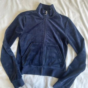Knappt använd mörkblå Juicy Couture tröja  - Jättefin mörkblå velourjacka från Juicy Couture i storlek S. Klassisk modell med dragkedja, hög krage och två fickor framtill. Även broderad JC-logga på bröstet. Använd fåtal gånger så nyskick, säljer då den tyvärr inte kommer till användning💕