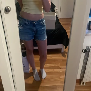 Blå lågmidjade jeansshorts - Snygga blå jeansshorts med fransig kant och slitna märkningar. De har midjemåttet 34cm och går både att ha lågmidjade som mid waist. Skriv om ni har fler frågor🥰
