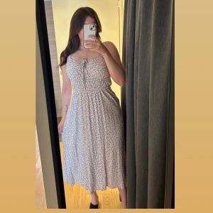 Blommig långklänning från & Other Stories - Supersöt långklänning från & Other Stories med blommigt mönster i rosa, grön och vit. Klänningen har smala axelband, knytning framtill och smockad midja. Perfekt för sommarens alla tillfällen. Luftigt material och flowy passform. Klänningen är nyligen köpt på secondhand för 350:- men tyvärr lite liten för mig. 