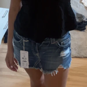 Jeanskjol - Snygga blå jeansshorts med slitna detaljer och fransig kant. Klassisk femficksmodell med låg midja och coola slitningar framtill. Perfekta för en avslappnad och trendig sommarlook. Använt ett få antal gånger. Säljer då jag vill köpa en större storlek. Pris kan diskuteras🤍