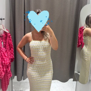 Lång virkad klänning i ljusgul - Superfin långklänning i virkad stil med smala axelband och rak halsringning. Klänningen är ljusgul och vit med ett genombrutet mönster och har en tight passform som framhäver figuren. Perfekt för sommarens alla tillfällen!