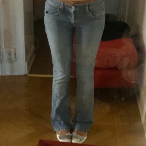 Ljusblå bootcut jeans med låg midja - Säljer ett par ljusblå jeans med bootcut och låg midja. Jeansen har klassisk femficksdesign, snygga slitningar och är i mjukt denimtyg. Passformen är normal och benen är lätt utsvängda nertill för en retro vibe.