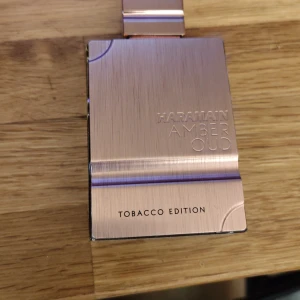 Haramain Amber Oud Tobacco Edition - Exklusiv parfym med varm, gyllene vätska i en stilren glasflaska. Locket är i metall med roséguldfinish och flaskan har en modern, fyrkantig form. Doften är Amber Oud Tobacco Edition, perfekt för dig som gillar rika och kryddiga toner. Inspirerad av tobacco vanille. 60ML 2ml använd ish