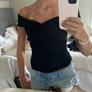 Svart offshoulder topp med twist - Säljer denna snygga offshoulder topp med twistad detalj framtill. Den sitter tight men har ett stretchigt material😙😙