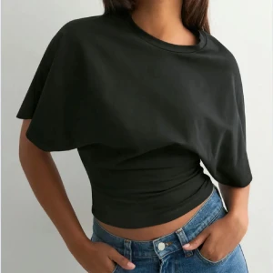 Svart  topp  - Snygg svart  topp med kort ärm och rund halsringning. Toppens passform är tight och den är tillverkad i mjuk bomull, perfekt att matcha med jeans eller kjol för en cool look.