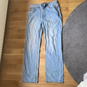 Abrand A 95 Baggy - Säljer ett par ljusblå jeans från Abrand med klassisk rak passform. Jeansen har fem fickor, bälteshällor och en liten svart Abrand-logga på bakfickan. Tillverkade i slitstarkt bomullsjeansmaterial, perfekta för en avslappnad streetstil.