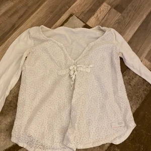 Vit Odd Molly blus med broderi och knyt - Supersöt vit blus från Odd Molly med broderade detaljer och knyt framtill. Långärmad modell med v-ringning och romantiskt hålmönster på framsidan. Perfekt för dig som gillar en feminin och bohemisk stil. Denna är köpt i Chicago när jag va utomlands men va inte direkt min stil men den är perfekt nu till sommaren.