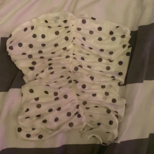 Vit topp med svarta prickar - Säljer en söt vit topp med svarta prickar. Toppen  har en rynkad design och korta ärmar. Perfekt för en somrig look! 🌼