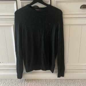 Mörkgrön tröja i merinoull från Morris - Säljer en stilren mörkgrön stickad tröja från Morris, tillverkad i merinoull. Tröjan har en klassisk design med rund hals och långa ärmar. En liten logga pryder bröstet för en diskret touch. Storlek är M men den skulle också kunna passa S. Inget slitage, ser som ny ut😁Priset är diskutabelt.