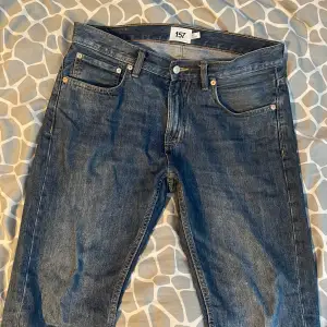 Säljer ett par klassiska blå jeans från 157. De har en normal passform med fem fickor och knappgylf. Perfekta för en avslappnad stil.