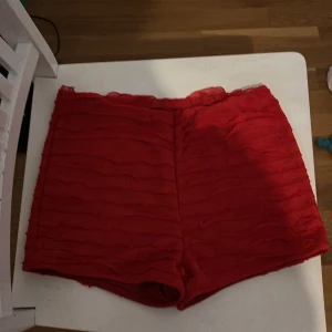 Röda shorts med volangdetaljer - Snygga röda shorts med volangdetaljer som ger en trendig look. Perfekta för sommarens alla tillfällen. De har en bekväm passform och är tillverkade i ett mjukt material. Kom nyss med posten och jag passade tyvärr inte i dom köptes för 150