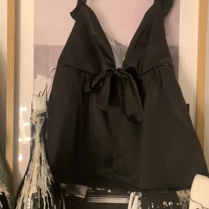 Svart satinlinne med knytband - Snyggt svart linne i satin med rosett framtilll, använd en gång! skriv om ni vill ha bild på, kan tänka mig gå ner i pris ❤️