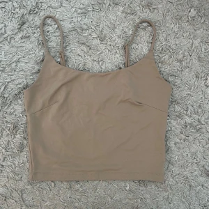 Beige linnetopp - Säljer en stilren beige linnetopp med smala axelband. Perfekt för varma dagar eller som ett basplagg i garderoben. Enkel och bekväm design som passar till det mesta. Använd fåtal gånger