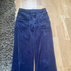 Mörkblå juicy couture byxor med snörning - Säljer ett par mörkblå juicy couture byxor med snörning i midjan och fickor både fram och bak. Byxorna har en loose passform och är perfekta för en avslappnad stil.🩷
