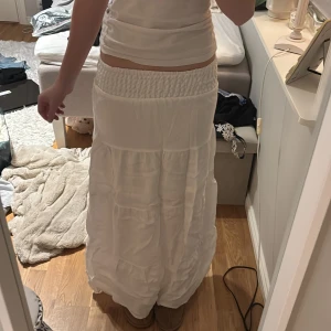 Vit långkjol med resårmidja - Säljer en vacker vit långkjol med resår i midjan för en bekväm passform. Kjolen har en luftig design och är perfekt för varma dagar. Den är tillverkad i ett lätt material som ger en fin rörelse.