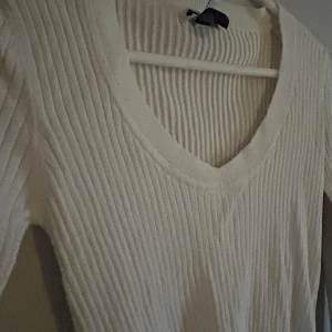 Vit ribbad tröja från MNG Basics - Säljer en stilren vit ribbad tröja från MNG Basics. Tröjan har en v-ringad design och långa ärmar, perfekt för en enkel och elegant look. Passar bra till både jeans och kjol. Perfekt för kyligare dagar! Mer som en Medium.
