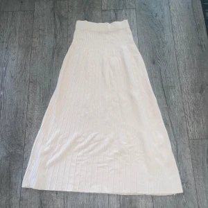 Krämvit kjol från Chiquelle - Säljer en elegant krämvit långkjol från Chiquelle. Kjolen har en ribbad design och är tillverkad i en mjuk blandning av viskos och nylon. Perfekt för sommaren. Jag skulle säga att det är en blandning mellan cream white och jätte ljus babyrosa.  Använd någon enstaka gång  XS-S  Från chiquelle