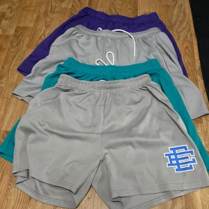 4 stycke Eric Emanuel shorts. - Jag säljer 4 stycken Eric Emanuel shorts i färgerna lila med gul logga, 2 gråa med blå logga och ett par turkosa med röd logga. Alla byxorna är storlek M. OBS snören på dom lila e borta. Shortsen är knappt använda 