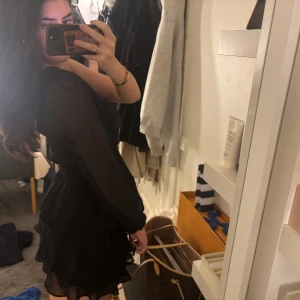 Svart oneshoulder klänning - Snygg svart oneshoulder klänning från ginatricot med volanger och lång ärm. Perfekt för en kväll ute eller en speciell tillställning. Storlek 36, använd en gång