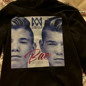 Svart hoodie med Marcus & Martinus tryck - Säljer en svart hoodie med stort tryck av Marcus & Martinus på framsidan. Väldigt skönt material och skön passform. Köpt på amazon 