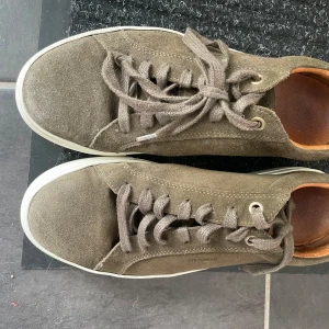 Gröna sneakers från Strömsberg - Snygga gröna sneakers i mocka från Strömsberg. Skorna har en klassisk design med snörning och en bekväm innersula i läder. Perfekta för en stilren vardagslook.