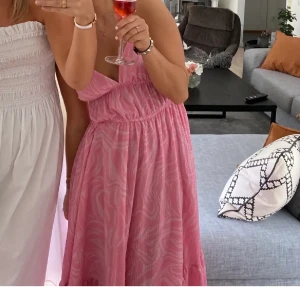Rosa långklänning HM - Säljer en rosa långklänning från H&M med subtilt mönster och v-ringad hals. Klänningen har smala axelband och en luftig passform, perfekt för varma dagar. Materialet är lätt och bekvämt, vilket gör den enkel att bära hela dagen. Storlek 38, (lånade bilder)💕🌸