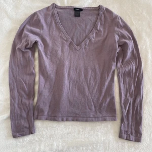 Ljuslila v-ringad tröja från Filippa K - Säljer en ljuslila långärmad tröja från Filippa K. Tröjan har v-ringning och är tillverkad i en mjuk bomull. Enkel och stilren modell som passar perfekt till många olika outfits.