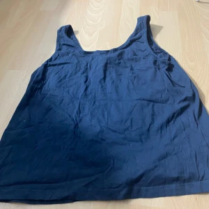 Mörkblå linnetopp från Beloved Nightwear - Säljer en enkel och stilren mörkblå linnetopp från Beloved Nightwear. Toppen är ärmlös med breda axelband och har en rak passform. Perfekt för varma dagar eller som ett basplagg i garderoben.