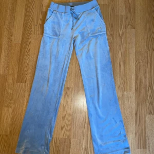 Juicy couture byxor blåa - Säljer mina juicy couture byxor. Storlek S, fick i julklapp 2023 och används aldrig längre. Lite slitna i nedre delen av baksidan på byxorna, se bild. Ena metallgrejen på snöret i midjan är borta, se bild. För mer bilder eller frågor, tveka inte att skicka ett meddelande!