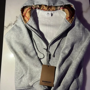Burberry Zip Up Grå - Säljer en stilren och klassisk grå zip-up från Burberry i storlek XS. Den har en tidlös design och är unisex, vilket gör att den passar både herr och dam. Perfekt för både vardagsbruk och en mer avslappnad, men ändå exklusiv stil. Tröjan är i fint skick och priset kan diskuteras vid seriöst intresse.