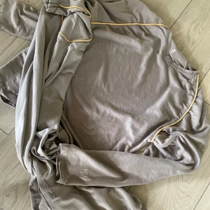 Beige mjukisbyxor med gula sömmar från KV - Säljer ett par grå mjukisbyxor samt t-shirt, kalsonger +strumpor och långärmad tröja från KV med snygga gula kontrastsömmar. Byxorna har resår i midjan och vid bensluten, samt broderad logga vid benet. Perfekta för en avslappnad stil. Allt är storlek S men passar även storlek M 