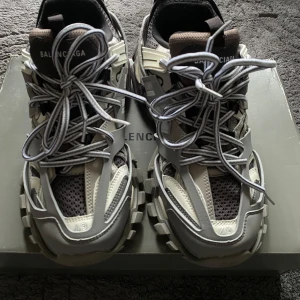 Balenciaga Track sneakers i grått och beige - Säljer ett par Balenciaga Track sneakers i grått, beige och svart med chunky sula och reflekterande detaljer. Skorna har mesh och syntetpaneler, stora snören och coola färgdetaljer i sulan som lyser upp. Perfekta för dig som gillar statement sneakers.
