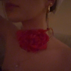 Rött choker-halsband med stor blomma - Säljer ett unikt choker-halsband med en stor röd tygblomma. Halsbandet har en tunn röd bandbas och är perfekt för att ge en statement-look. Passar dig som vill sticka ut och addera färg till din outfit. Perfekt för temafester som capitol osv! Från Appear på Åhléns. 99kr orginalpris