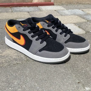 Air Jordan 1 Low SE 'Black Vivid Orange' - Säljer ett par Nike Air Jordan 1 Low med grå, svart och orange färgkombination. Nästan helt ny, använt den några gånger. Perfekta för dig som gillar streetwear och snygga sneakers. Tyvärr ingen låda.