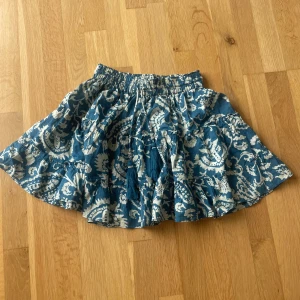 Blåvit mönstrad kjol från Gina Tricot - Supersöt blå och vit kortkjol från Gina Young med med tofsar och pärldetaljer. Kjolen har ett unikt mönster och resår i midjan för extra komfort. Perfekt för sommaren.