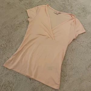 Rosa T-shirt - Hej! Säljer denna supersöta rosa v-ringade t-shirten då den helt enkelt inte kommer till användning. Perfekt nu till våren och sommaren när man vill se lite extra brun och fräsch ut!🤩Den är endast använd 1 gång och har därav inga defekter. Om ni skulle ha några frågor är det bara att höra av er annars går det superbra att trycka på ”köp”.💓💓💓