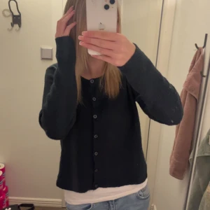 Mörkblå kofta med knappar - Säljer en enkel och stilren mörkblå kofta med knappar framtill. Koftan har lång ärm och en rak passform.