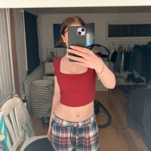 Röd croppad ribbad topp - Säljer en röd croppad topp med ribbad struktur och korta ärmar. Toppen har en fyrkantig ringning och sitter tight. Perfekt att matcha med jeans eller kjol.