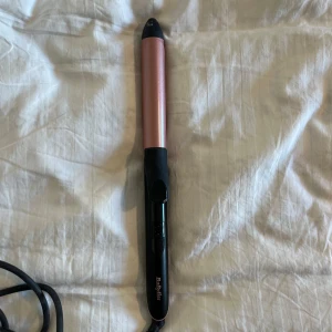 Locktång från BaByliss i roséguld - Snygg locktång från BaByliss i roséguld och svart. Cylindrisk form med klämma. Perfekt för att skapa mjuka lockar. Sladd medföljer. Använd en gång, så som ny i skicket.