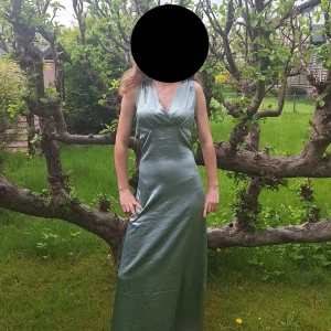 Ljusgrön långklänning i satin - Säljer en elegant LJUDSGRÖN lågklänning i satin med v-ringning och ärmlös design. Prislappen är kvar. Klänningen har omlott-detalj framtill och en djup v-ringning i ryggen. Perfekt till bal. Fråga gärna om mer bilder 💗 Nypris 600 kr💗